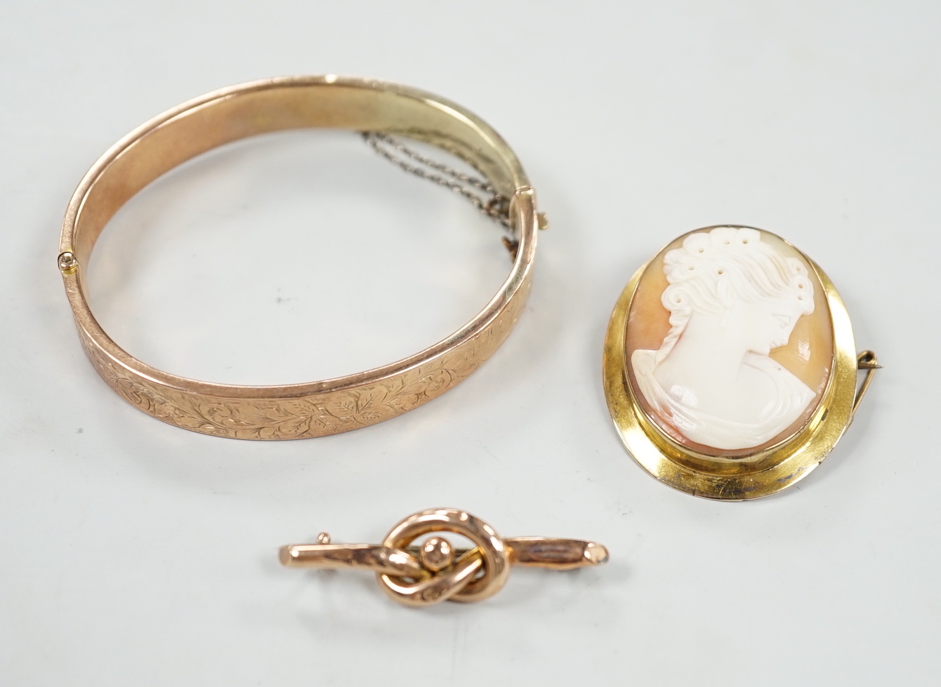 A 9ct mounted oval cameo shell brooch, 41mm, a 9ct gold bangle and a 9ct knot brooch